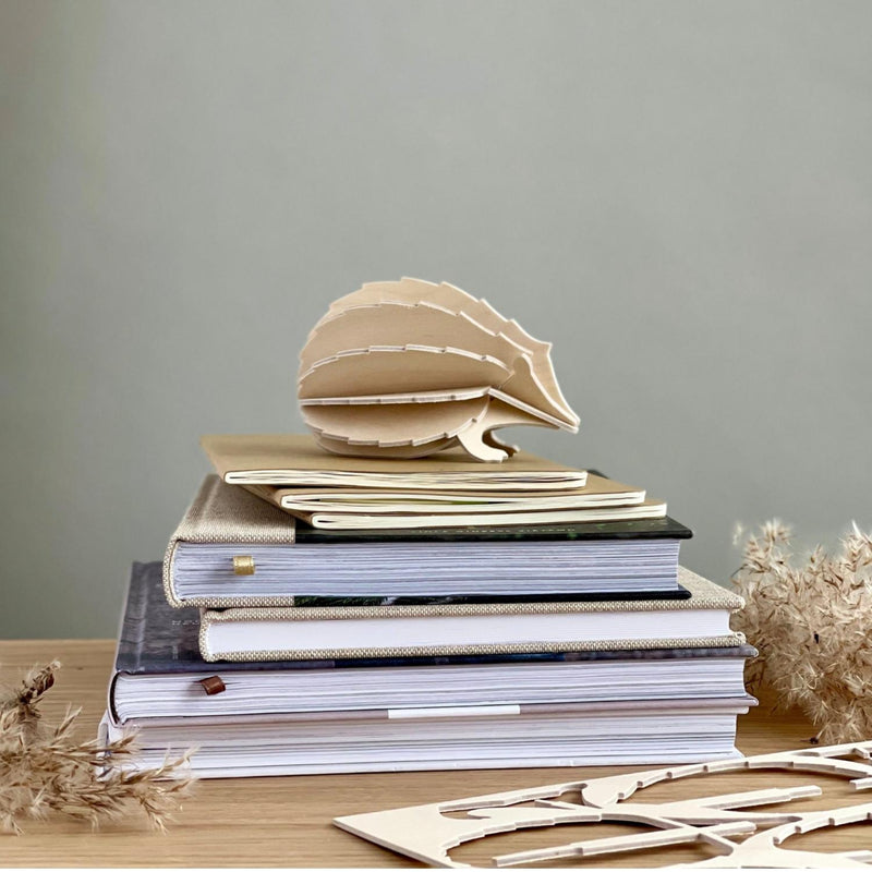 Lovi HEDGEHOG (3.1" / 8 cm) in natural wood color on top of books