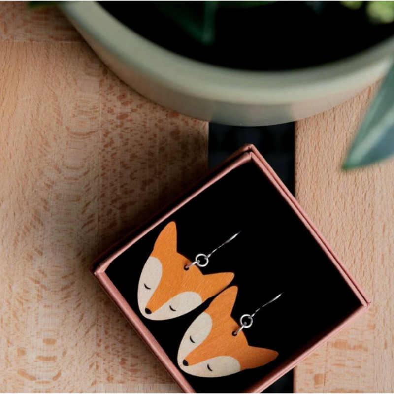 Rae Factory KETTU Earrings in orange made of Finnish birchwood with silver hooks in a case on the table