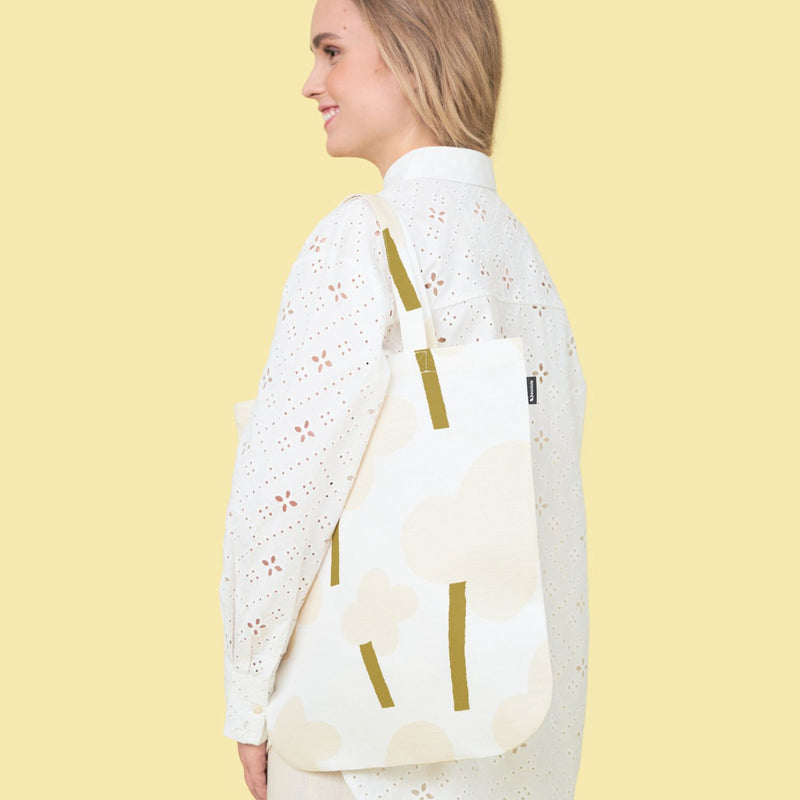 Kauniste ONNI linen-cotton toteback in light grey color on a model against yellow background