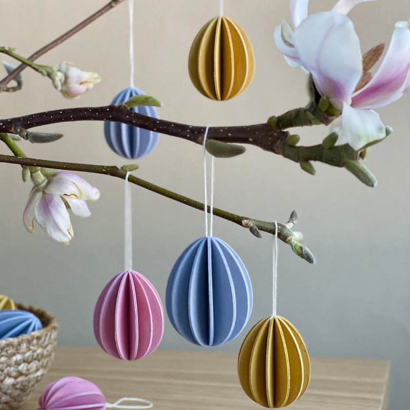 Small and large Lovi Easter eggs hanging on a branch in pastel hues