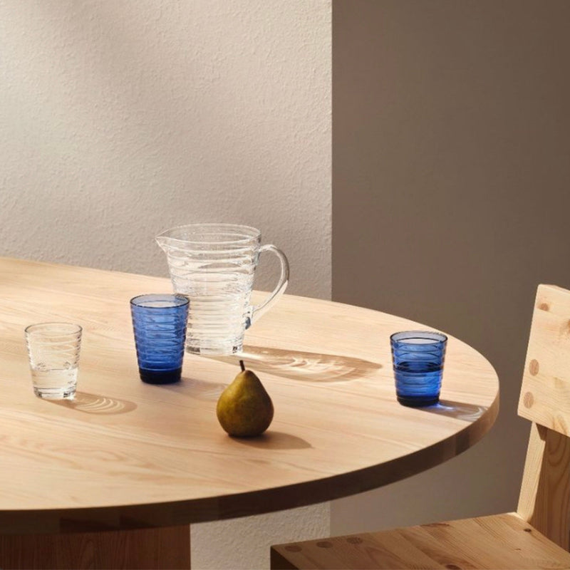 Iittala AINO AALTO (1932) Tumblers (11oz and 7.75 oz) in ultramarine and clear colors with Aino Aalto Collection pitcher on an oak dining table